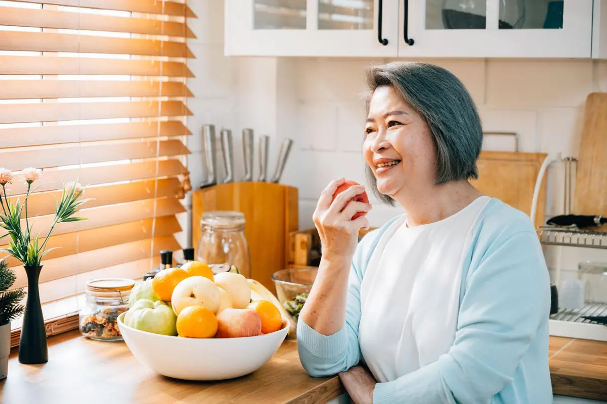 A woman smiling in her kitchen with a bowl of fresh fruit