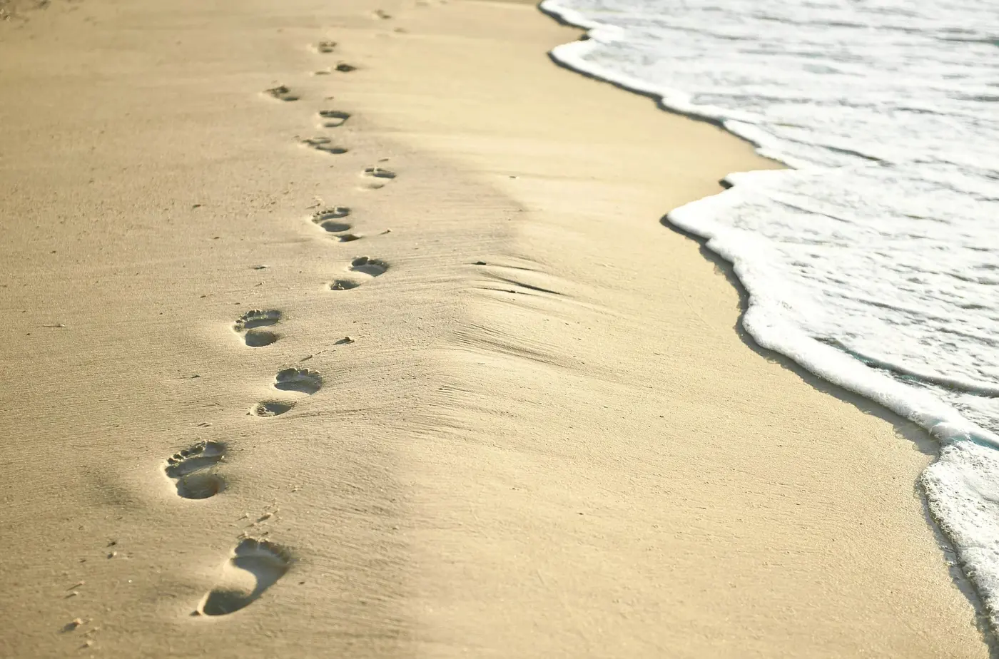 Footprints along the edge of the sea on smooth sand