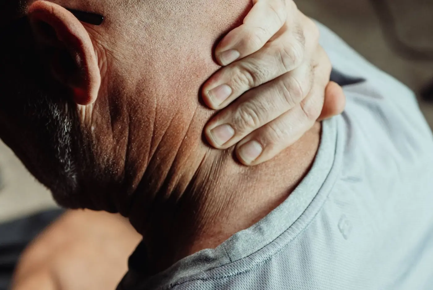 A practitioner's hand easing tension at the side of a patient's neck